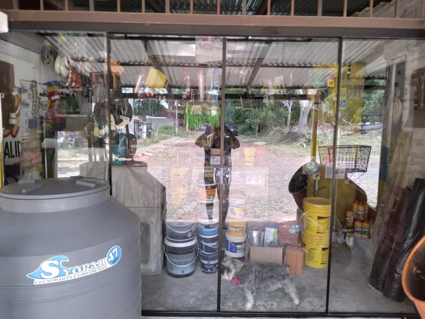 Vidriera de Fe y Je con un tanque de agua, baldes de pintura y herramientas colgadas
